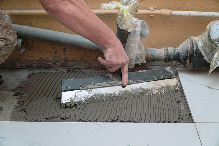 A construction worker applies cement for laying floor ceramic tiles with a special spatula