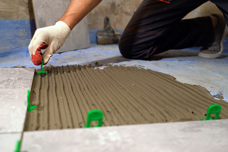 Installation of fasteners between tiles on the floor. Installation of a leveling system on ceramic tiles on the floor. Worker hands placing spacers between ceramic floor tiles. Installing a large ceramic tile.